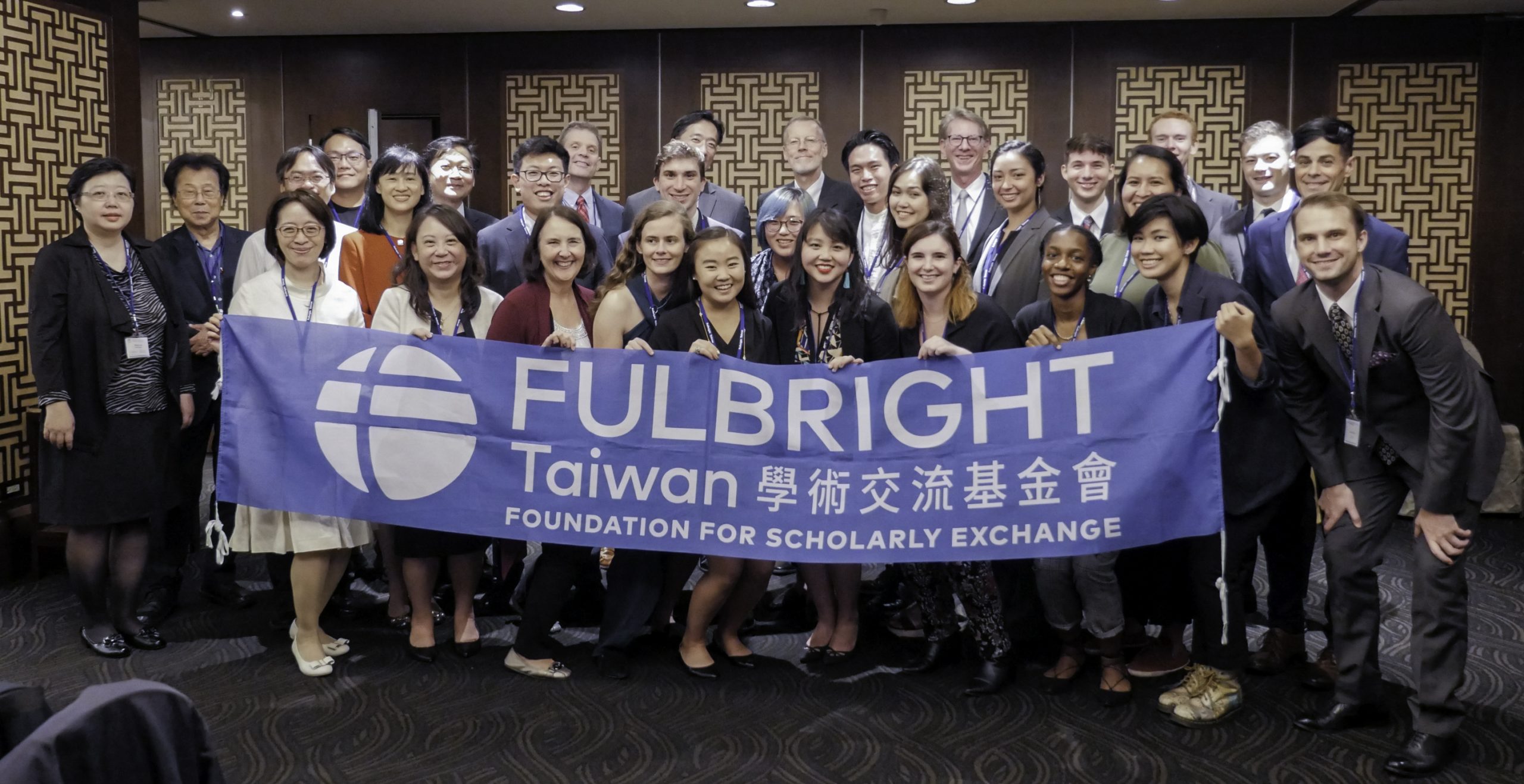 A group of men and women smiling and holding a large blue banner that says Fulbright Taiwan Foundation for Scholarly Exchange in English and in Chinese characters