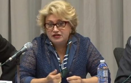  Hilda Ochoa-Brillembourg discusses the role of educational exchange in regional advancement at a panel hosted by the U.S. Department of State in 2013. She wears eyeglasses and is mid-sentence, speaking into a mic.