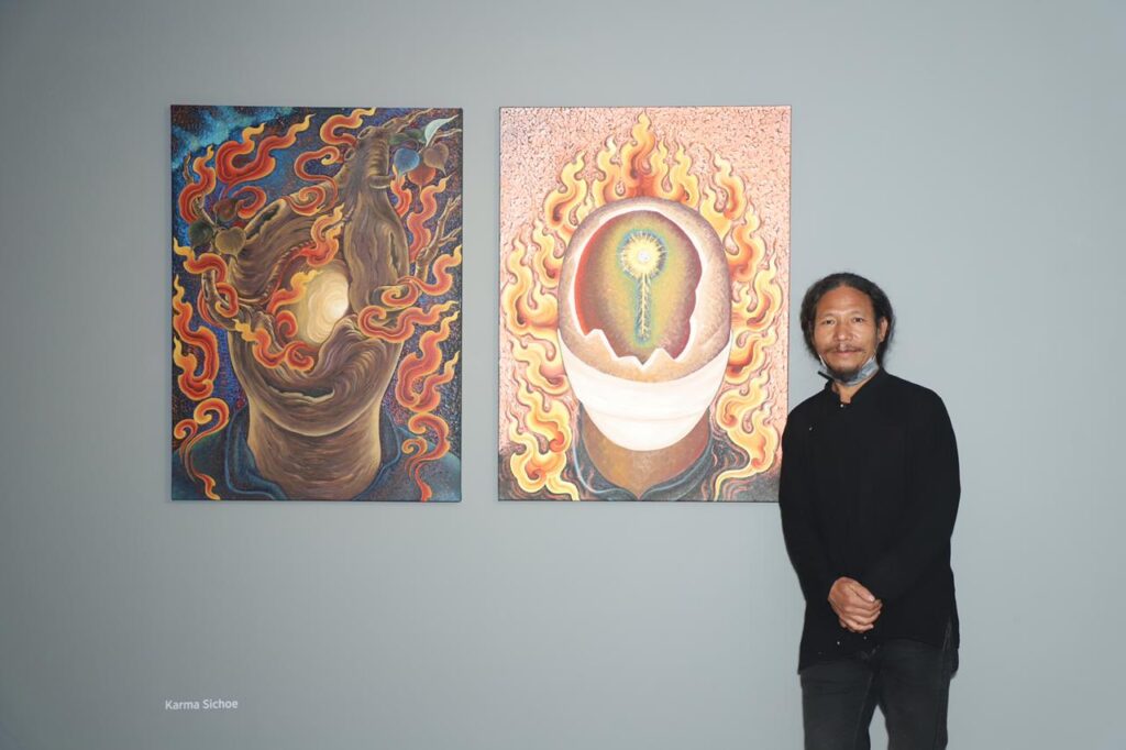 Man standing next to two paintings hung on the wall