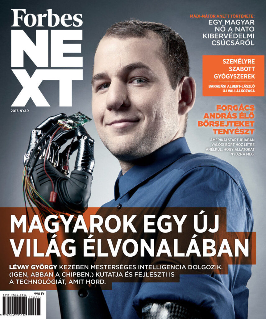 Forbes NEXT magazine cover in Hungarian with Headshot of György Lévay with one of his mechanical upper limb prostheses - a robotic-looking hand and wrist on the cover