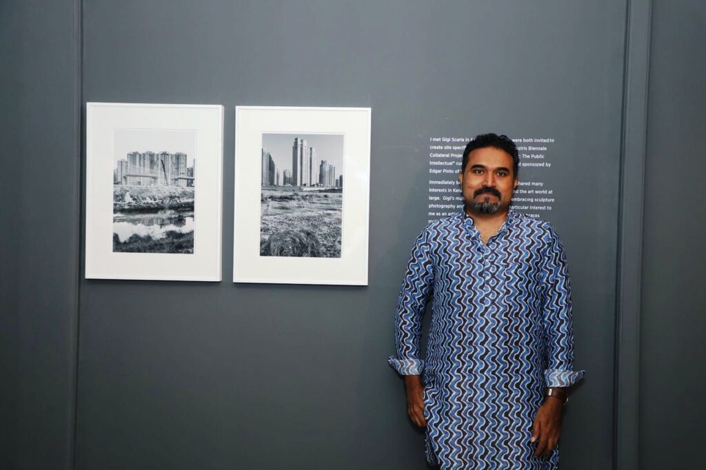 Man standing next to two artworks on the wall